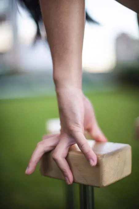 Close-up of hand of female gymnast balancing on blocks outdoors