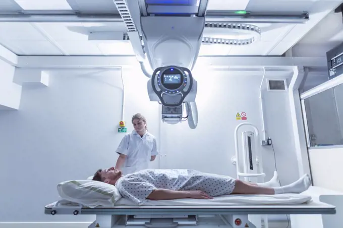 Radiologist assisting patient atÊx-ray machine in hospital