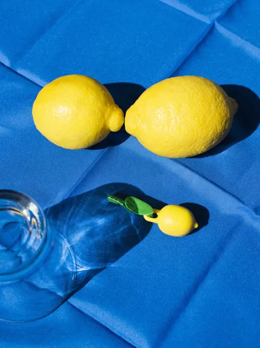 Still life with glass and lemons on blue tablecloth