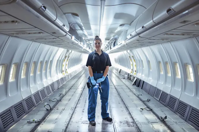 Portrait of apprentice aircraft maintenance engineer in empty interior of jet