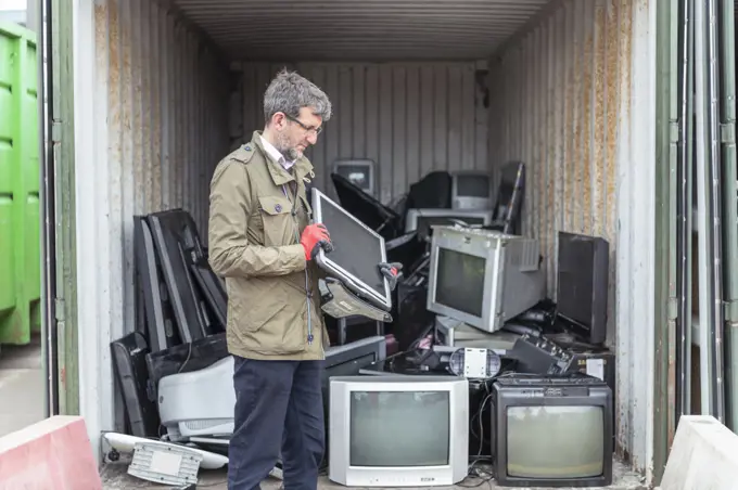 UK, Grimsby, Man holding old computer monitor at recycling center