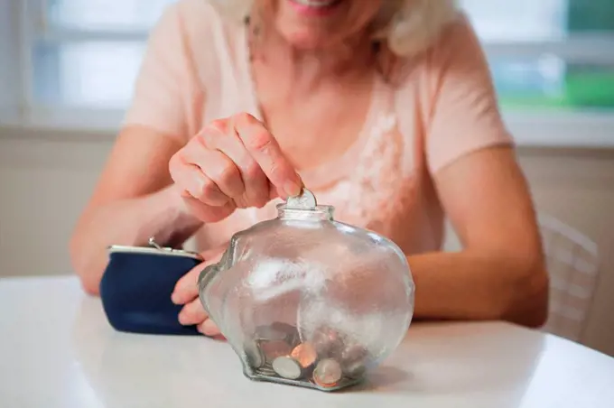 Senior woman saving money in piggy bank
