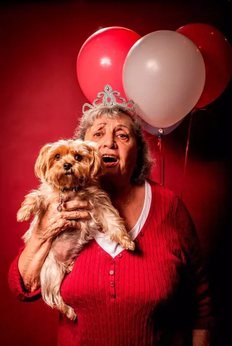 Senior woman holding dog and wearing a tiara