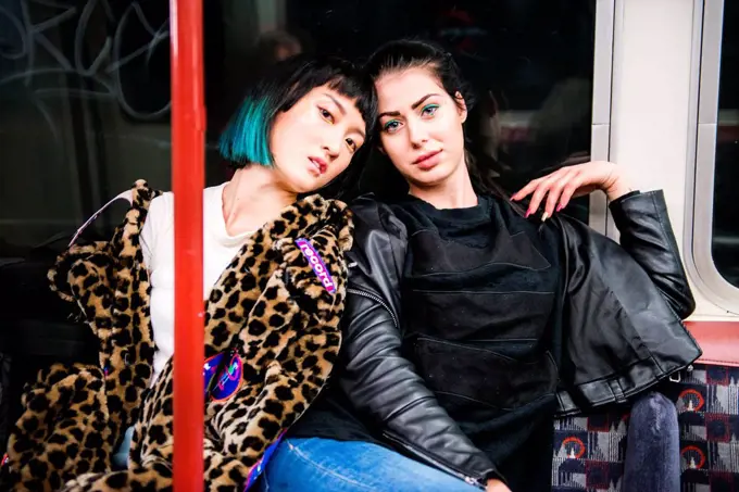 Portrait of two young stylish women on underground train carriage