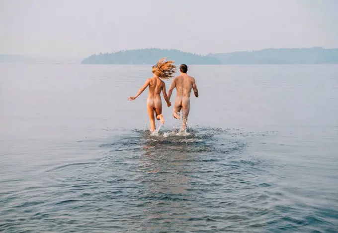Rear view of nude couple running into water
