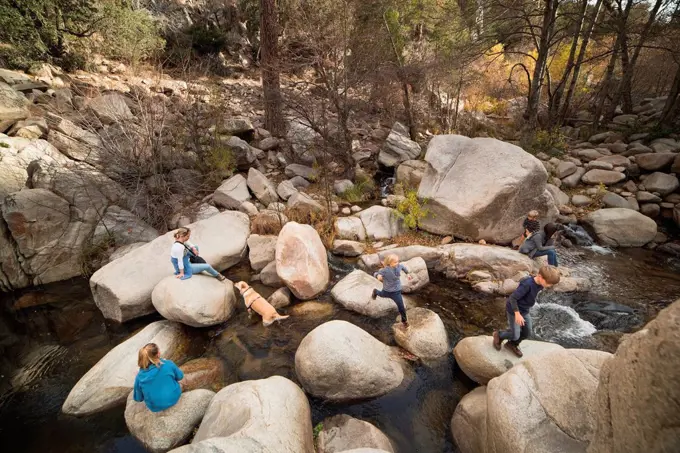 Family playing on rocks in river, Lake Arrowhead, California, USA