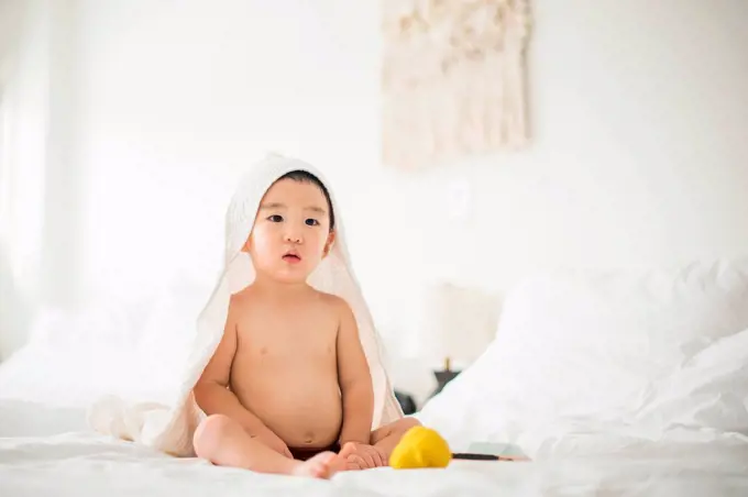 Little boy with hooded towel in bed