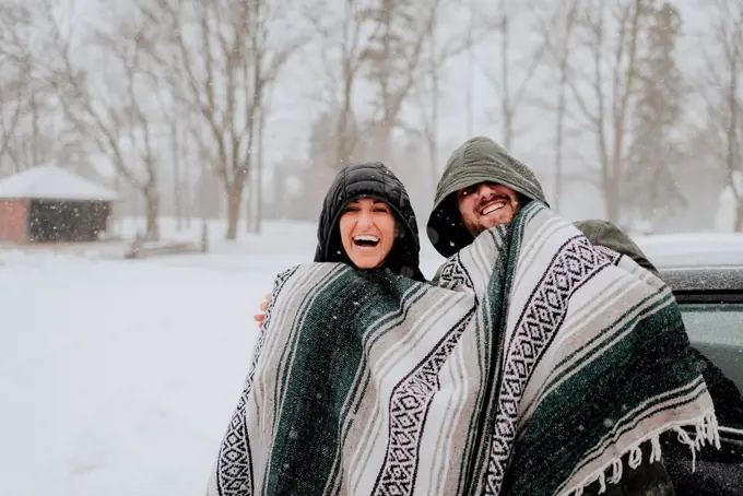 Couple wrapped in blanket in snowy landscape, Georgetown, Canada