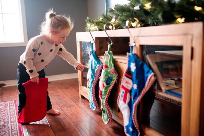 Toddler girl hanging up Christmas stockings