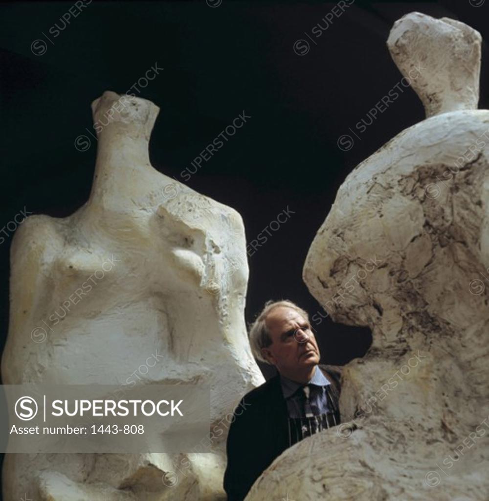Stock Photo: 1443-808 Henry Moore in His Studio Between Original Casts of His Sculptures "Relief No. 2" & Seated Woman" 1966 Artist Unknown Photograph
