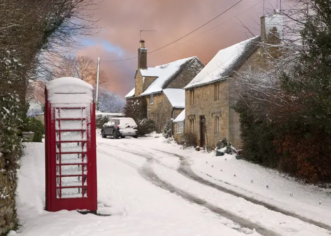Red phone box and cottages in snow, Cotswolds, Gloucestershire, England.
