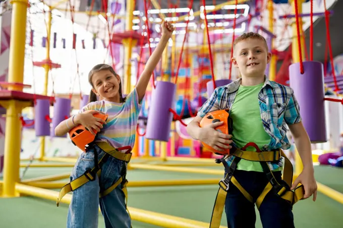 Two children poses in climbing area in entertainment center, young climbers. Boy and girl having fun on ropes, kids spend the weekend on playground, happy childhood. Two children poses in climbing area, young climber
