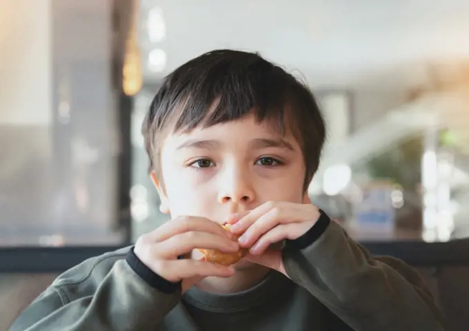 Portrait Kid bitting hash brown for breakfast, Healthy Child boy eating English Breakfast in the cafe or restaurant, Healthy food concept