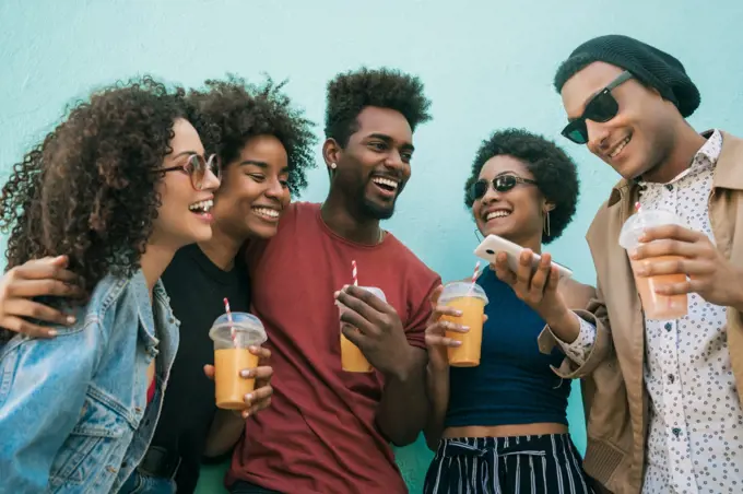 Portrait of afro friends having fun together and enjoying good time while drinking fresh fruit juice. 