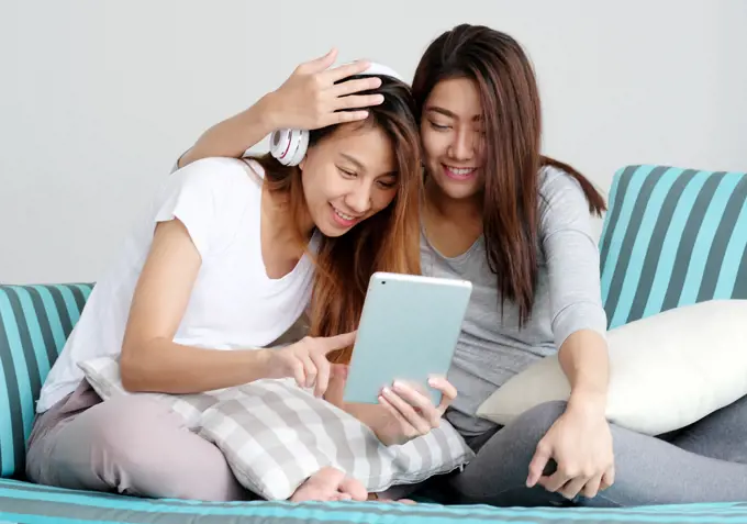 LGBT, Young cute asian lesbian couple wearing headphone and using tablet with happy moment, homosexual, lesbian couple lifestyle