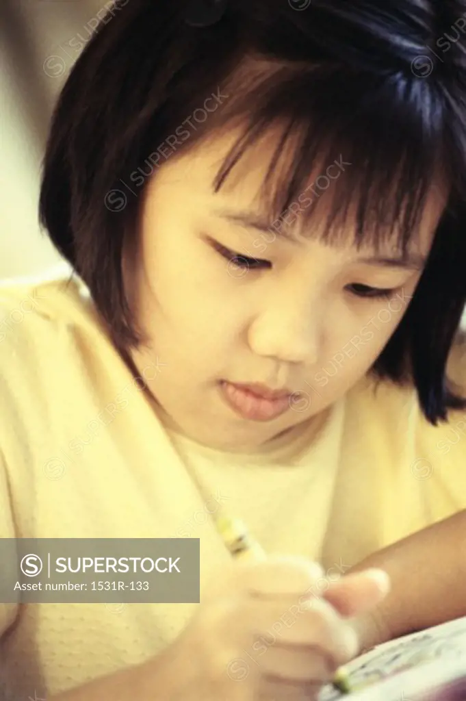 Close-up of a girl sitting at table coloring with crayons