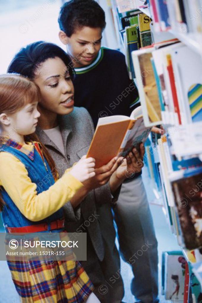 Stock Photo: 1531R-155 Female teacher reading a book with two students