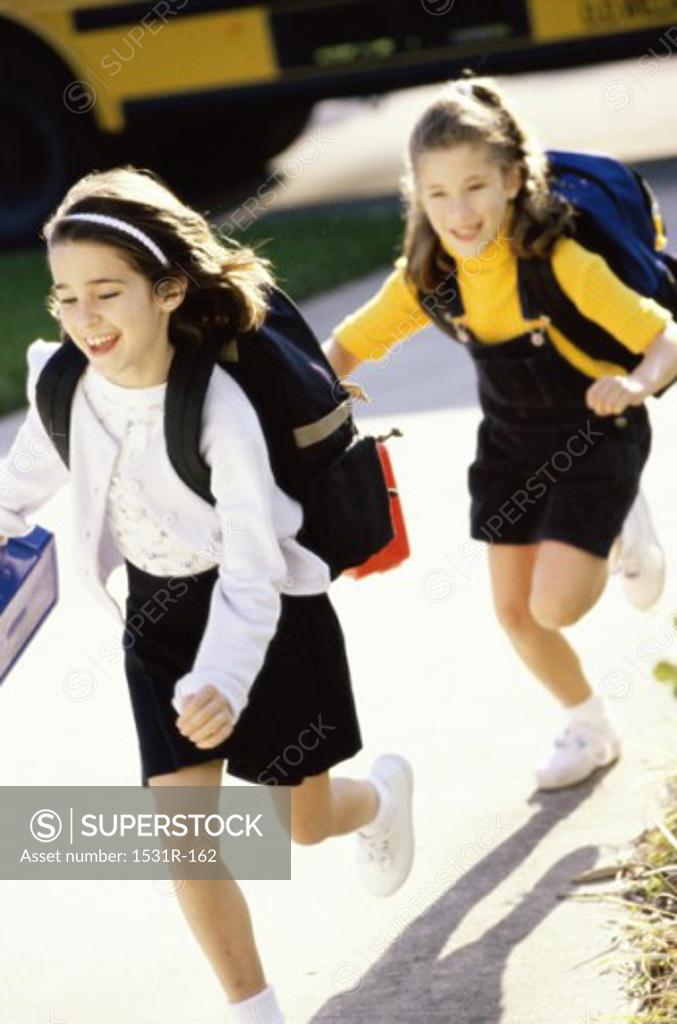Stock Photo: 1531R-162 Two girls running with school bags on their backs