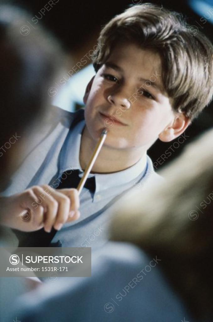 Stock Photo: 1531R-171 Boy sitting in a classroom with a pencil against his chin