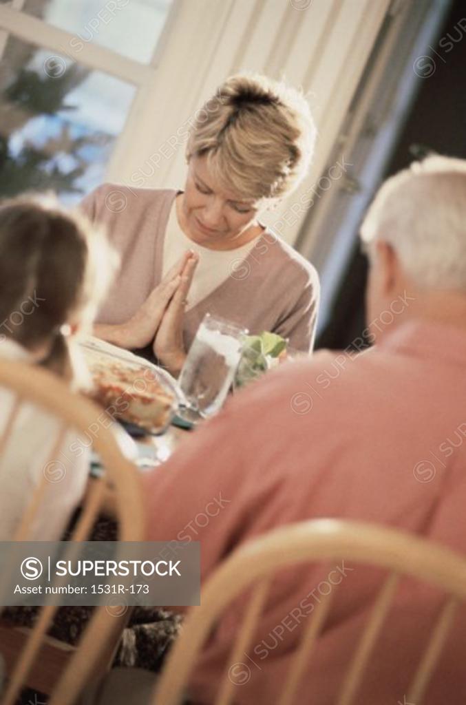 Stock Photo: 1531R-173 Family sitting at the dining table praying