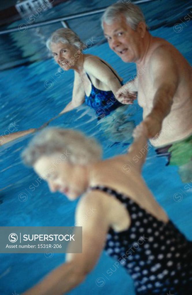 Stock Photo: 1531R-206 Portrait of a senior man holding hands with two senior women in a swimming pool