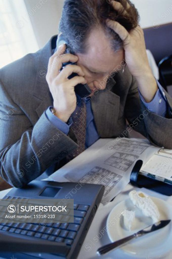 Stock Photo: 1531R-233 Portrait of a businessman seated behind an office desk talking on a telephone