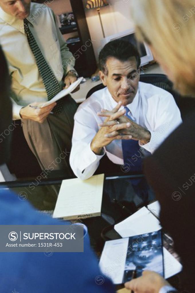 Stock Photo: 1531R-453 Businessman sitting with business executives standing around him