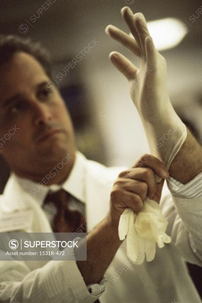 Stock Photo: 1531R-472 Male surgeon putting on surgical gloves