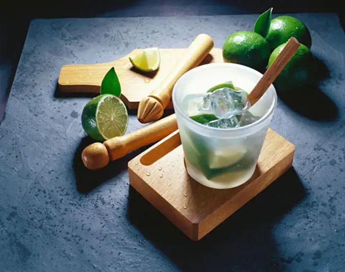 Limes and ice cubes in a glass with a pestle