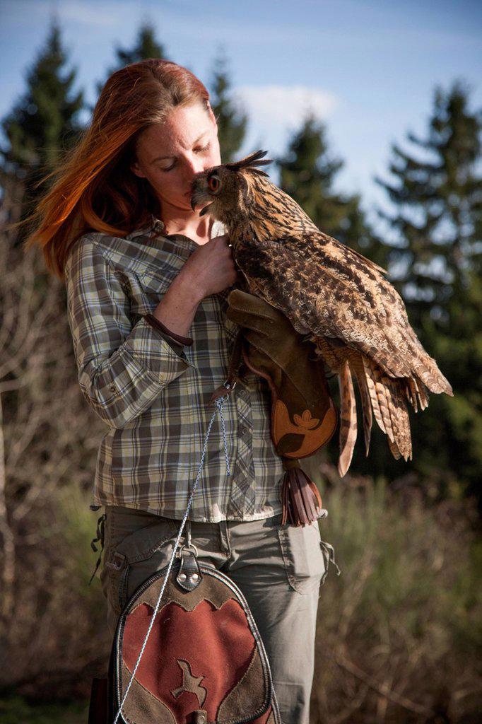 Falconer holding eagle owl on the hand and stroking him