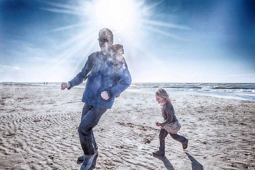 Father and daughter are running on the beach