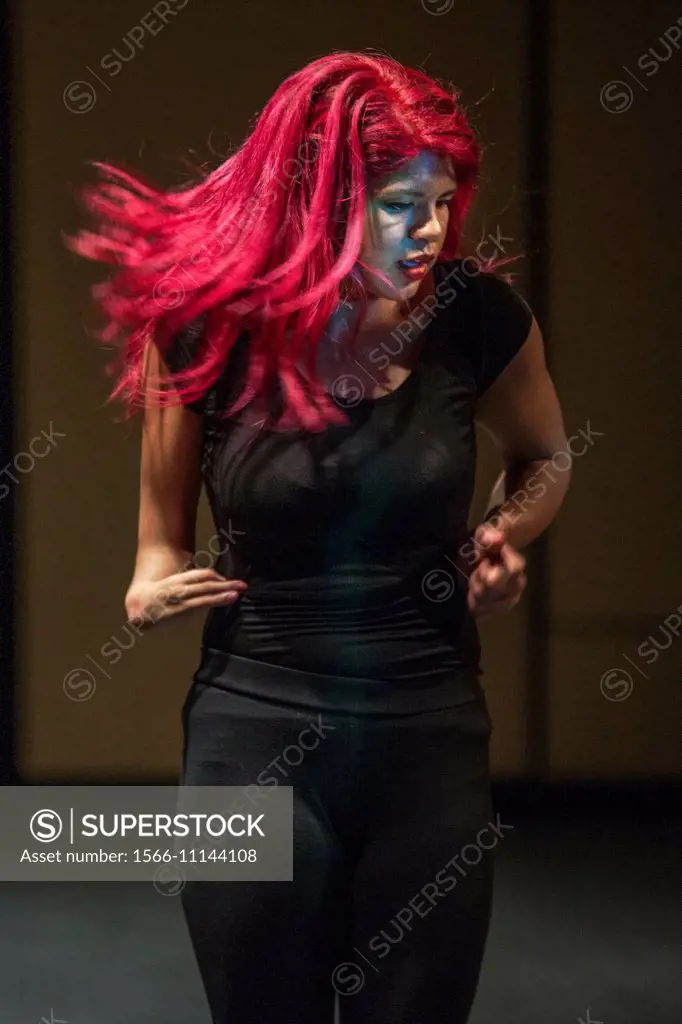 A Hispanic high school dancer performs on stage at a talent show in San Juan Capistrano, CA. Note makeup and magenta hair.