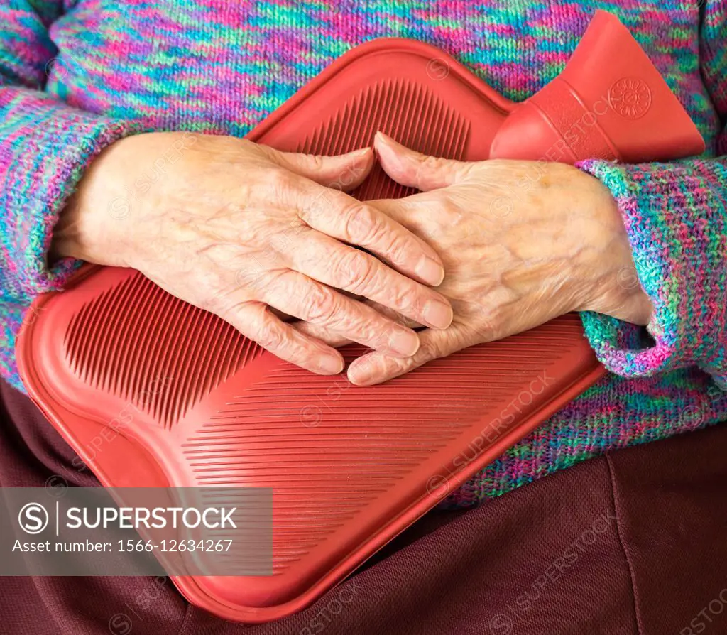 Elderly woman holding hot water bottle. England, UK.