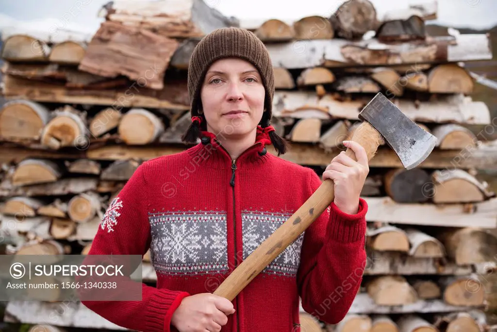 Female hiker nordic style holding axe to cut firewood at mountain hut, Kungsleden trail, Lappland, Sweden. - SuperStock