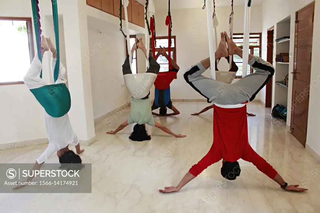 An aerial yoga class practicing Supta Baddha Konasana.