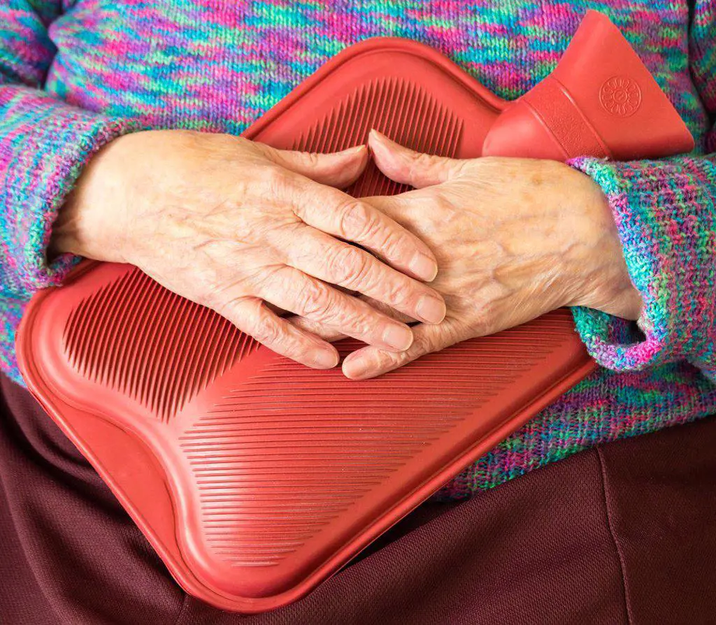 Elderly woman holding hot water bottle. England, UK.