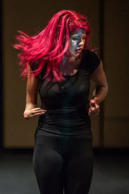 A Hispanic high school dancer performs on stage at a talent show in San Juan Capistrano, CA. Note makeup and magenta hair.