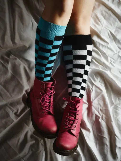 Girl lying on the bed and she wearing the socks and the pink shoes.