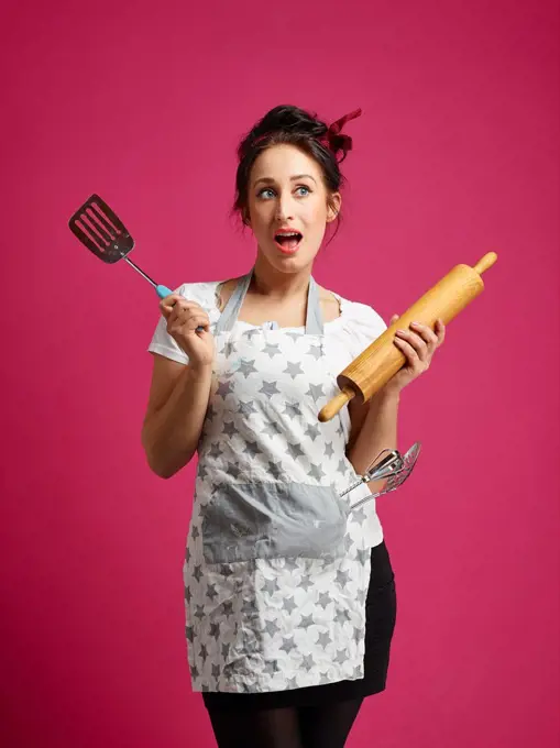 Funny housewife and kitchen utensils, pink background.