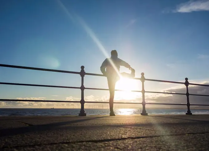 Seaton Carew, north east England, United Kingdom Jogger stretching at sunrise on a bright and cold winter morning at Seaton Carew on the north east co...