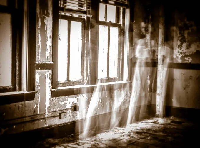 A ghostly figure of a woman in a white dress moving a room in an abandoned building.