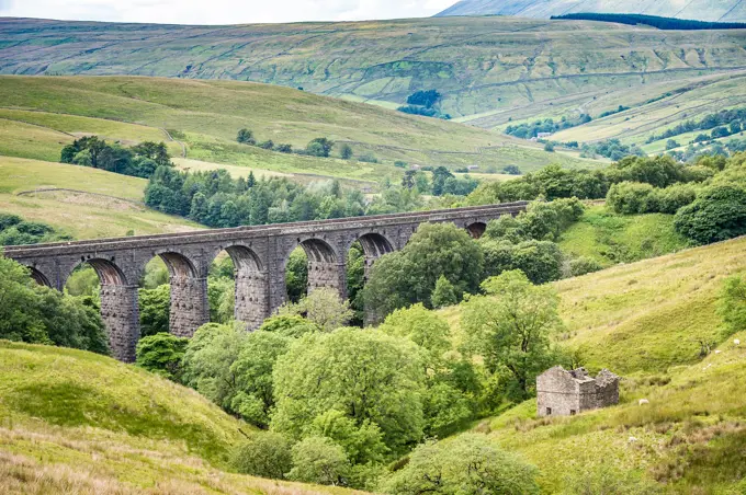 Extensive stone bridge allows for trains to cross over rolling hills of the Dales, Yorkshire Dales, UK.
