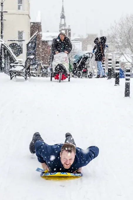 A local man sledging in the high street, Lewes, Sussex, UK.