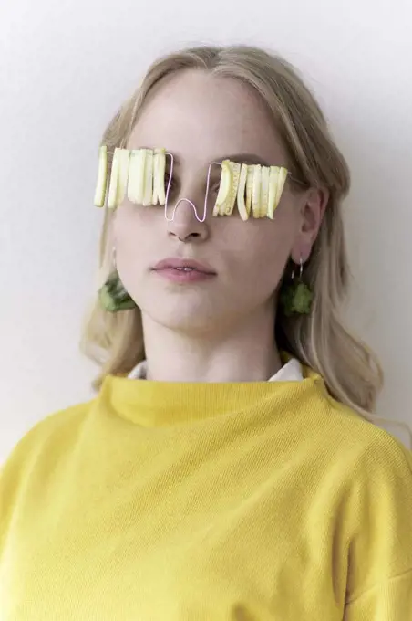 young woman wearing natural sunglasses and earrings made of raw zucchini