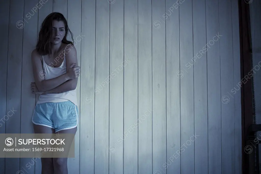 Sad young woman standing in bedroom