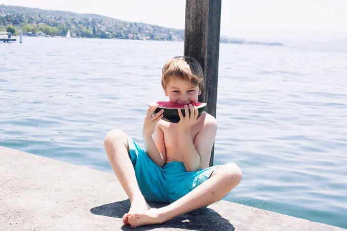 Boy eating watermelon on dock