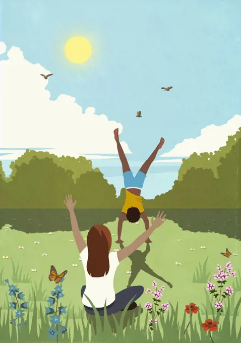 Woman cheering for man doing handstand in sunny, idyllic springtime meadow
