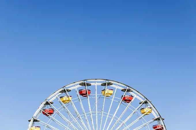 Low angle view of Ferris wheel against clear blue sky