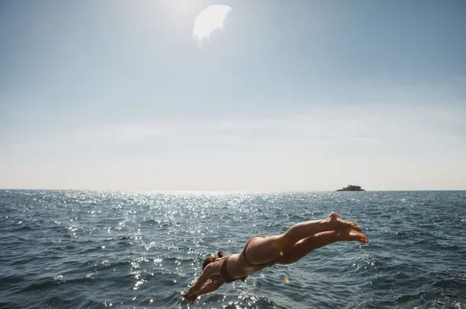 Woman diving into sunny blue ocean, Rovinj, Croatia