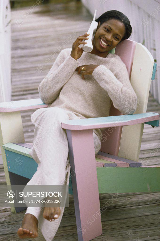 Stock Photo: 1574R-0018320 Young woman sitting in a chair talking on a telephone
